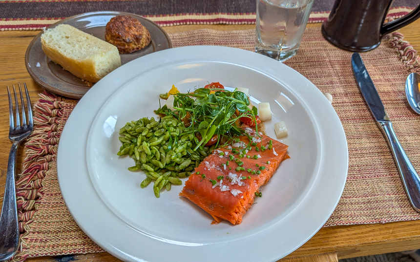 Plate of salmon with rice and a small side of breads with a fork and knife