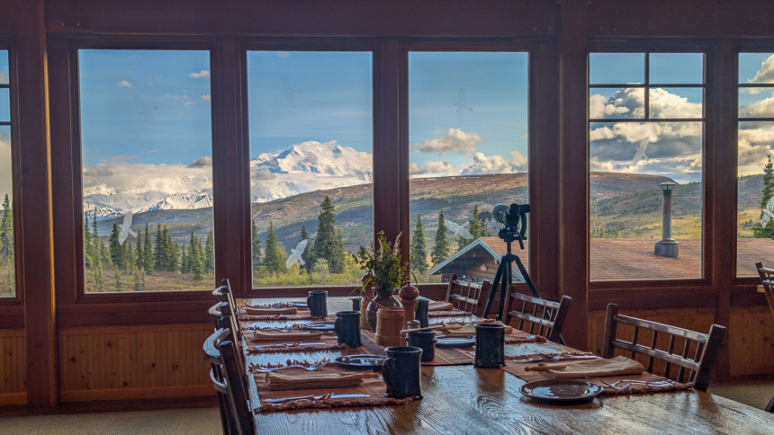 Wooden dining room table over looking out at mount denali on a sunny day