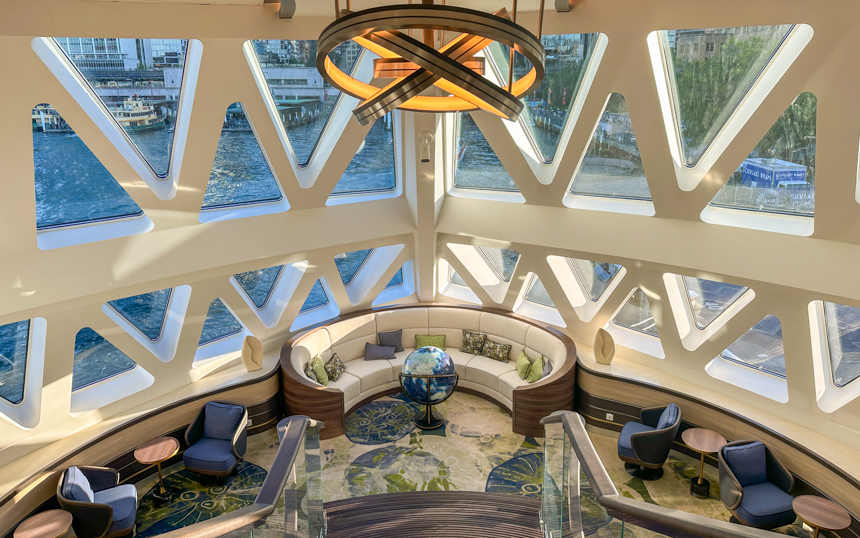 Honeycomb design windows aboard Douglas Mawson with an open seating area with couches, small seating areas and a large globe in the center