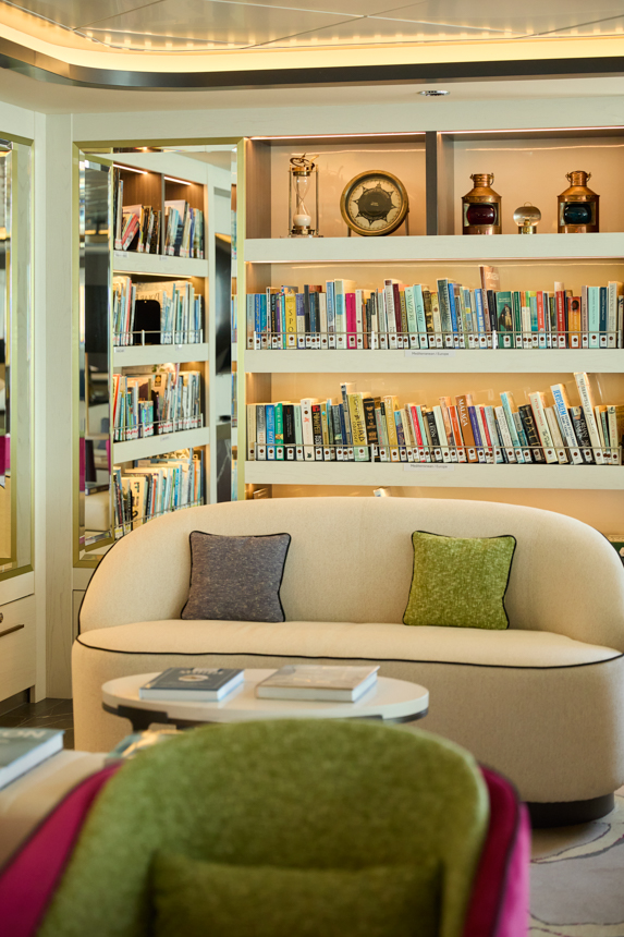A cozy library aboard Douglas Mawson with couches, shelves of books, and expedition design elements with nice warm lighting 