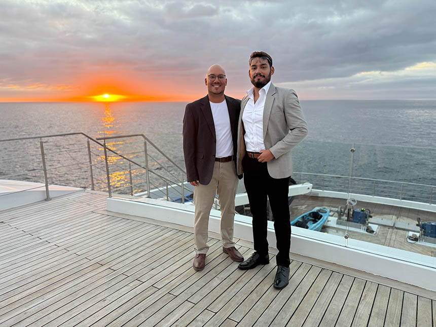 Two male Galapagos national park guides dressed up on the bow of Hermes catamaran
