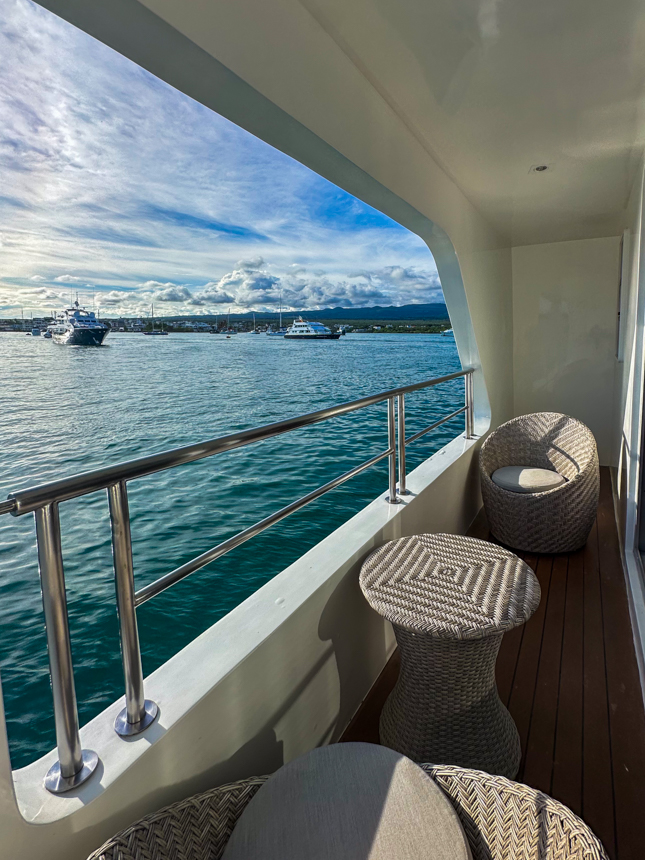 Balcony views with seating for two and small table aboard small cruise ship looking out at the marina on a sunny day 