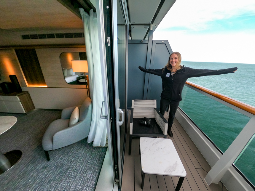 Split view of Deluxe Suite showing private balcony attached to room with sliding glass door and glass barrier chairs and table.