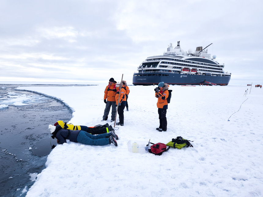 at the edge of an ice sheet at the north pole a group takes water samples for a science research project. 