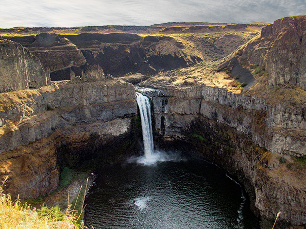 A waterfall spills from a cliff down into a pool of water
