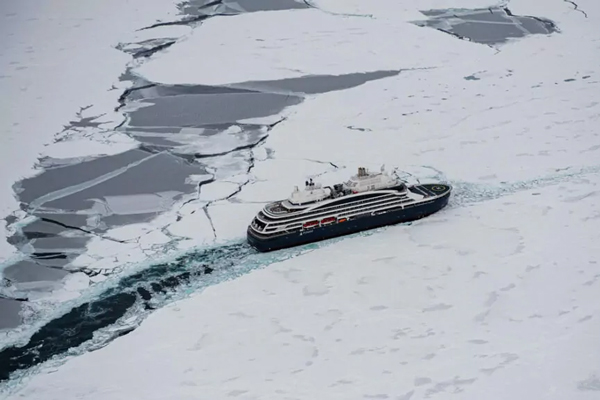Aerial view of modern icebreaker small expedition ship Le Commandant Charcot breaking through ice in a polar climate.