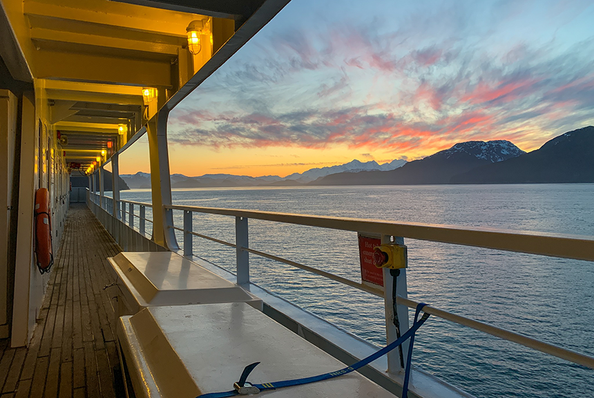 From the outside deck of Safari Endeavour looking out over the water is a pastel sunset setting over the snow covered mountain range, 