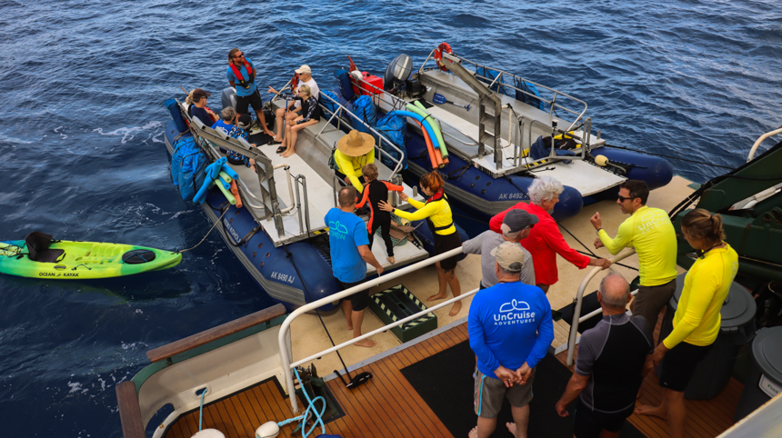 small cruise ship floating in Hawaiian ocean loading guests onto smaller boats off the safari explorer 