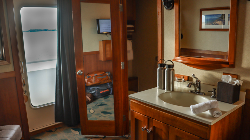 Small cruise bedroom with bathroom attached and brown wood and views to the deck
