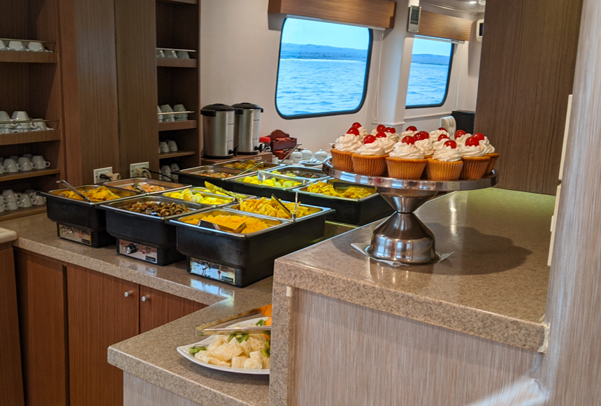 Lunch buffet set up aboard Seaman Journey a tray of cupcakes, and warming trays of food.