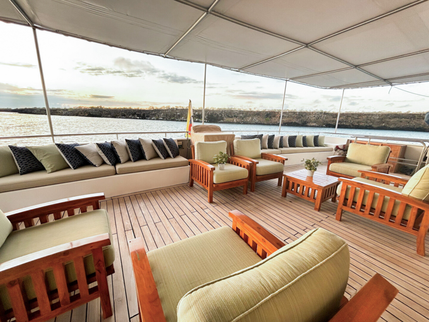 the aft outdoor bar and lounge on the upper sun deck of Seaman journey with wooden chairs with green pads.
