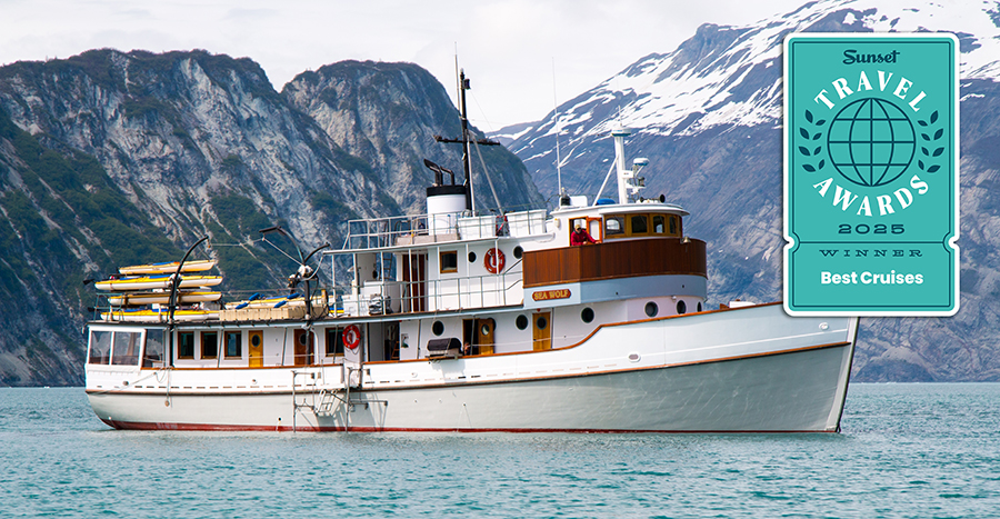 Small wooden ship Sea Wolf in Glacier Bay National Park Alaska surrounded by mountain range, 