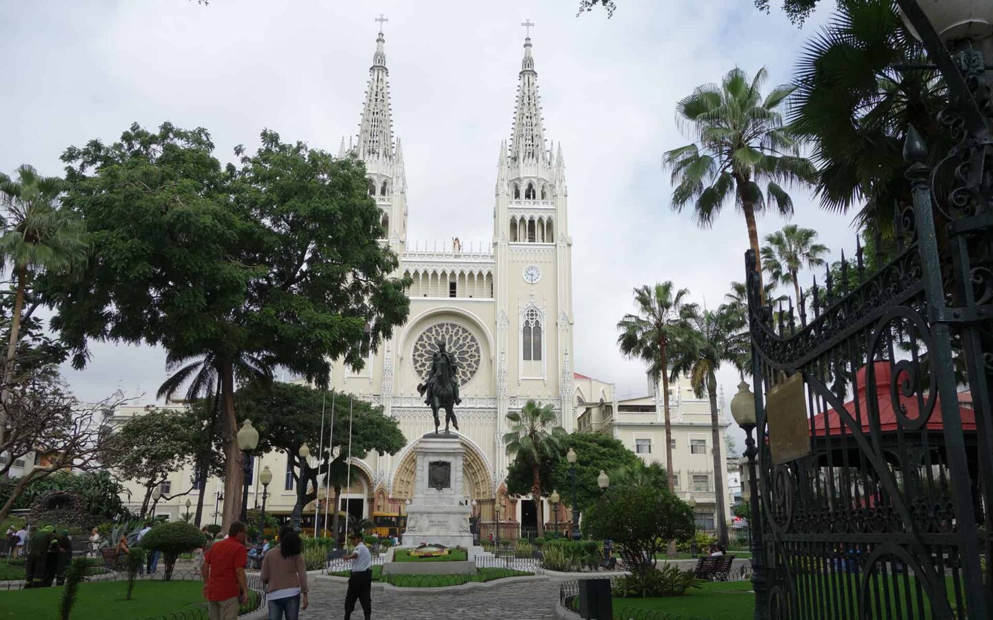 white church with two towers in guayaquil with ecuador travelers walking around it and trees in the foreground