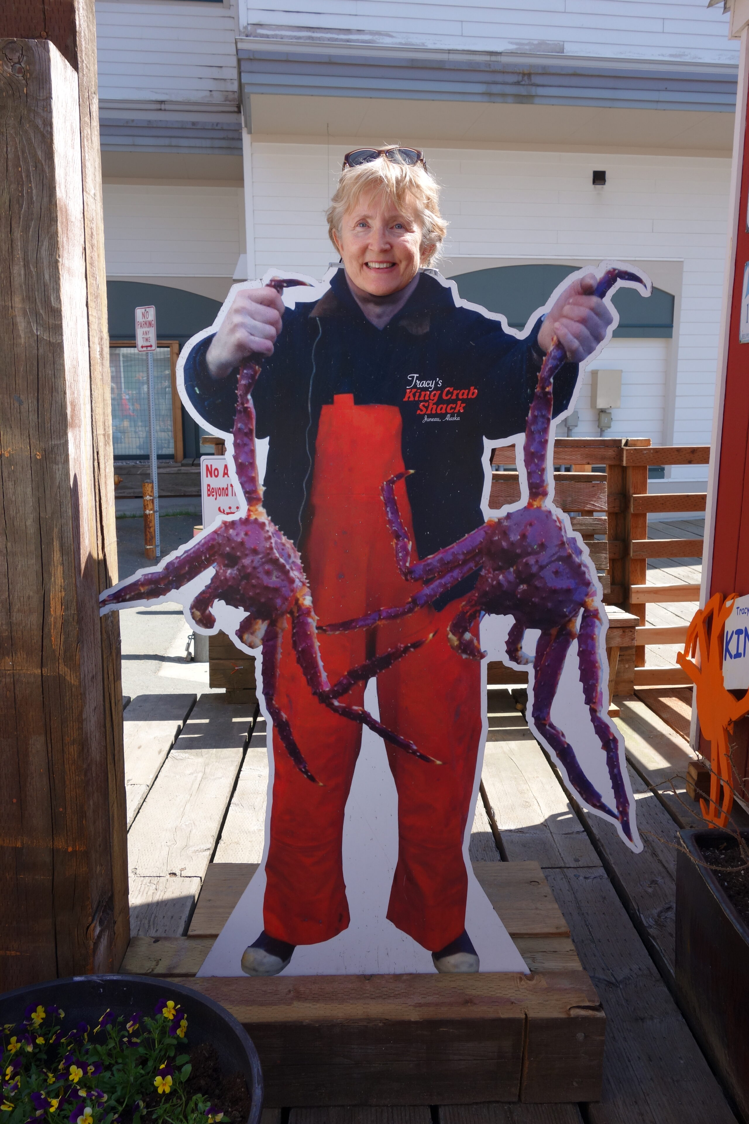 An older blonde woman poses at Tracy's Crab Shack's photo display looking like you are a crab fisherman