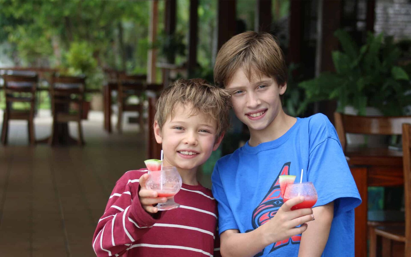 two boys stand smiling holding drinks made of fresh fruit in costa rica