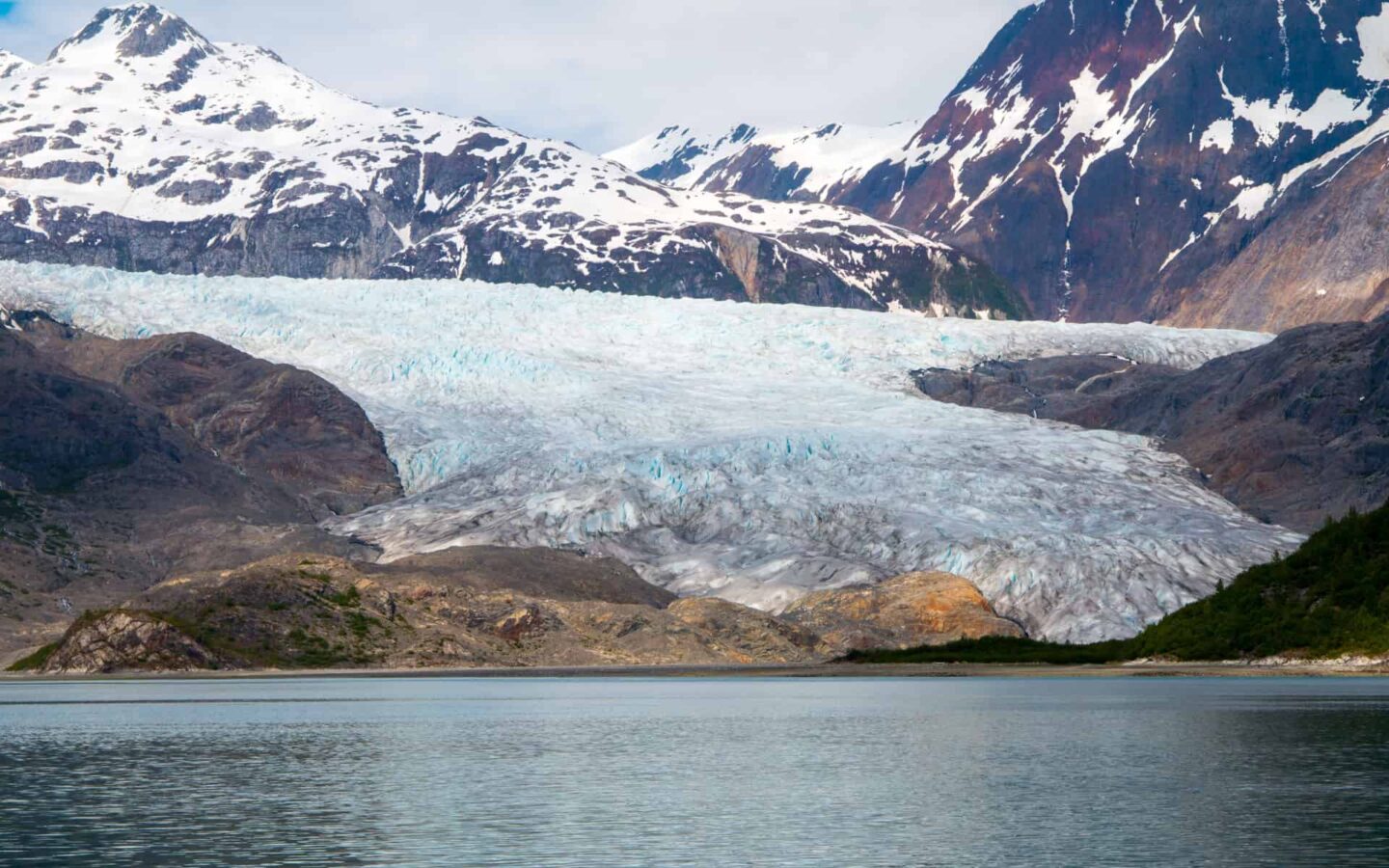 alaskan glacier on a sunny day with large mountains in the distance