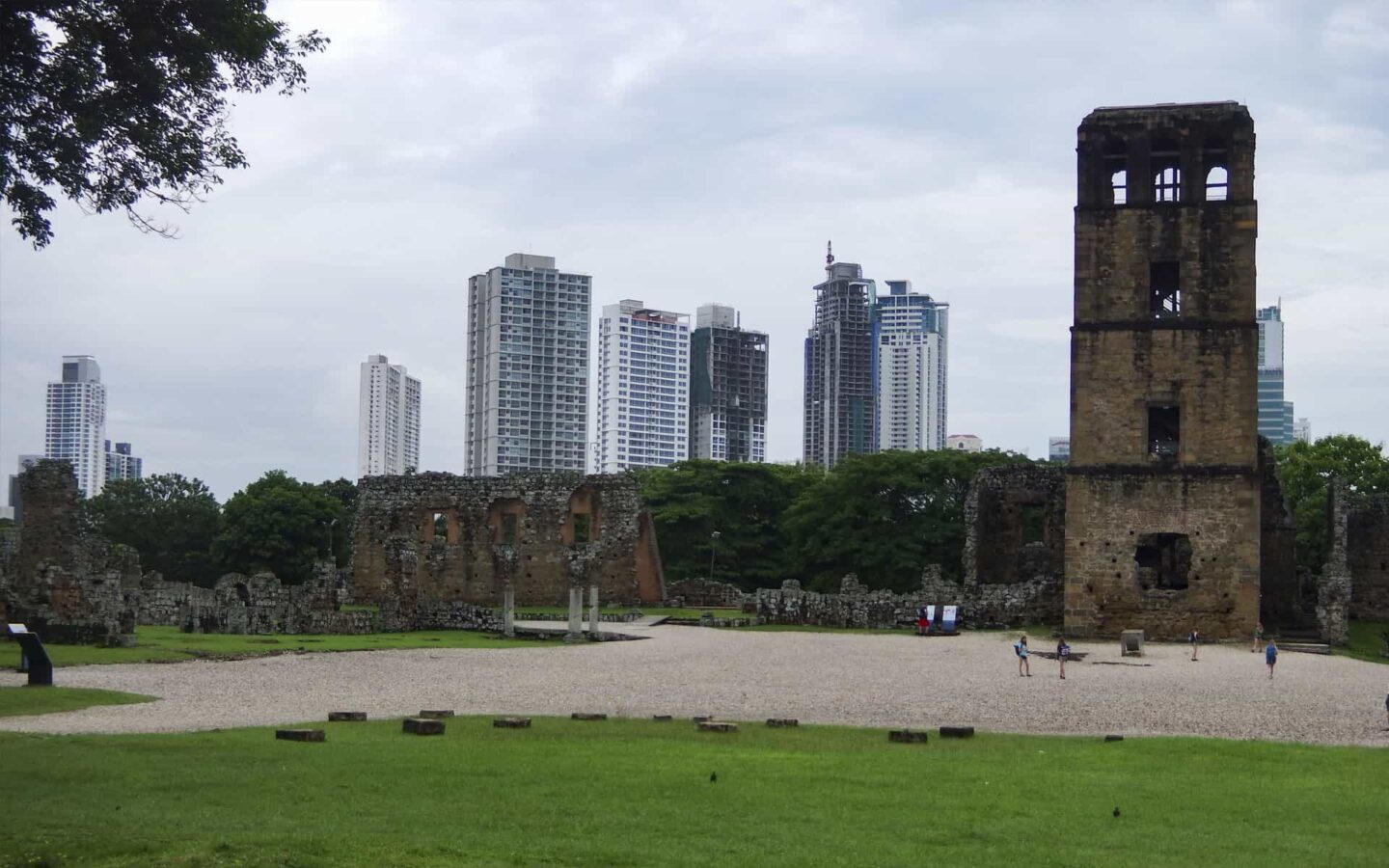 juxtaposition of an old panama fort with travelers walking around it and new skyscrapers directly behind it