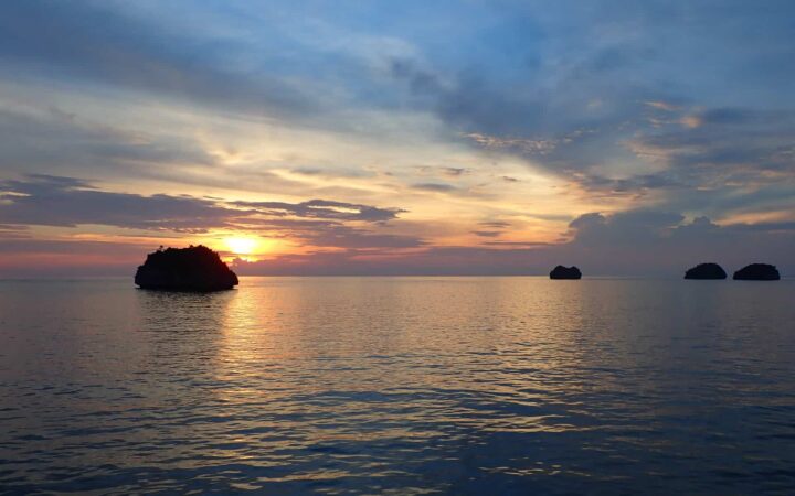 cruising the great barrier reef in australia at dusk with light shining through clouds over a calm ocean
