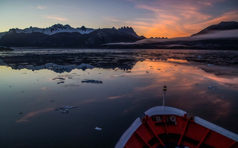 Sunset over Patagonia from a Chile cruise aboard a small ship with icebergs around it.