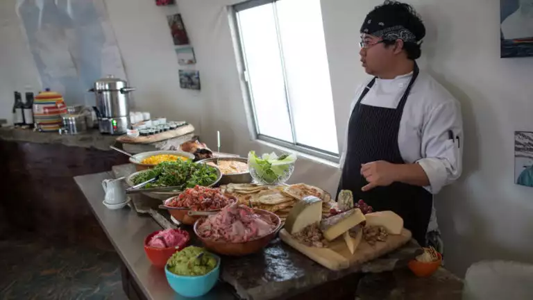 A server with a table of buffet foods at Arctic Watch Lodge.