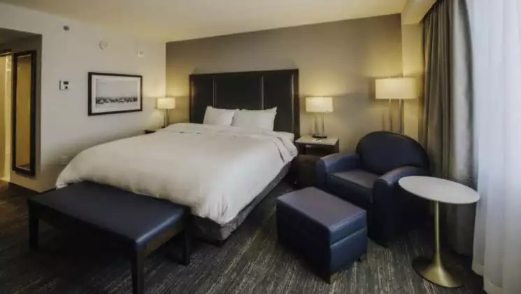 Bed near armchair and ottoman bathed in natural light in Deluxe Suite at Explorer Hotel in Yellowknife, Northwest Territories