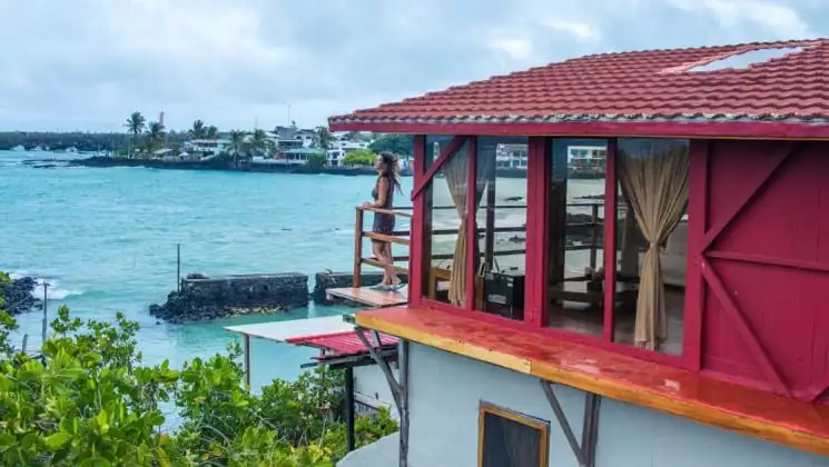 Woman stands on balcony outside her oceanfront suite at Galapagos Habitat Eco Luxury Hotel on Santa Cruz in the Galapagos Islands