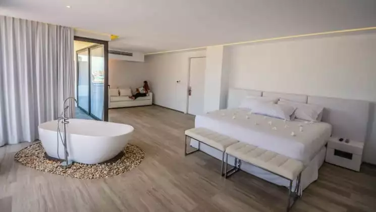 Suite interior with bed, couch, bench & large tub in middle of room at Golden Bay Galapagos hotel on San Cristobal in the Galapagos Islands.