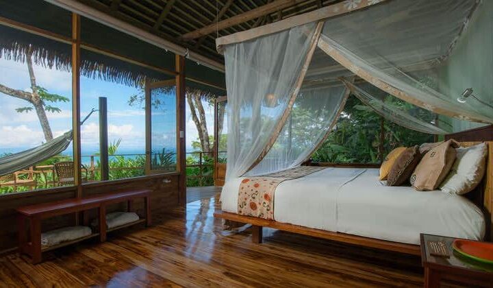 A room with a king-sized bed, balcony, hammock, and oceanview at Lapa Rios Eco Lodge, in Costa Rica's Oso Peninsula