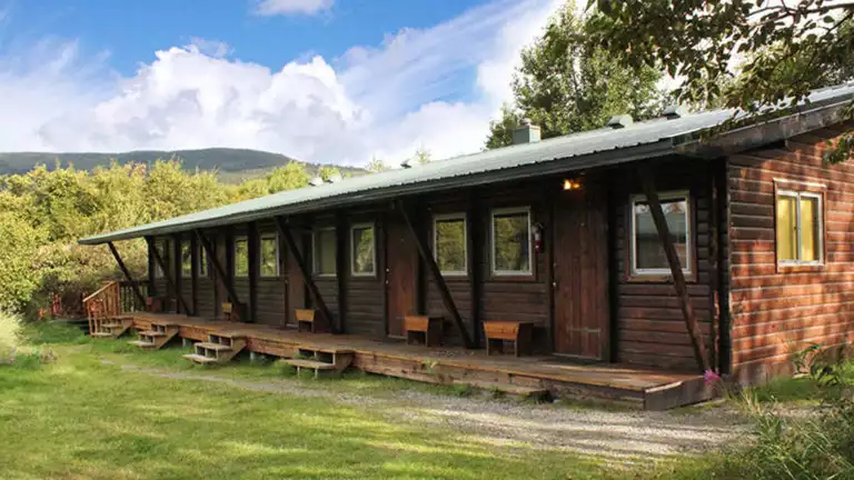 A row of wood cabins that are located near a river at the Brooks Lodge in Alaska