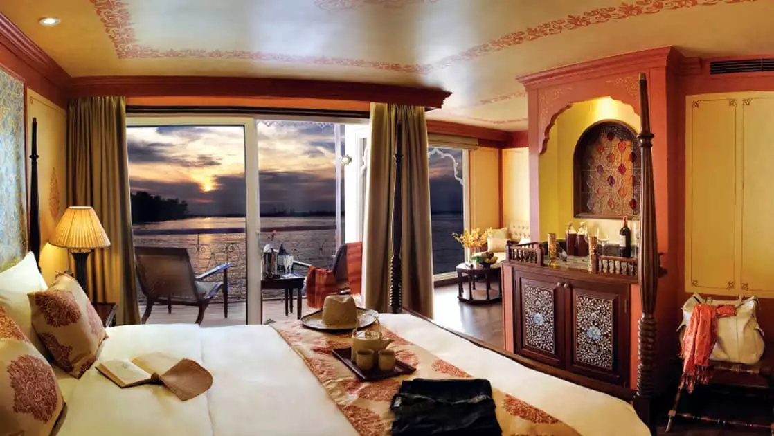 Jahan Category 2 stateroom with queen bed, dresser, balcony with 2 chairs.