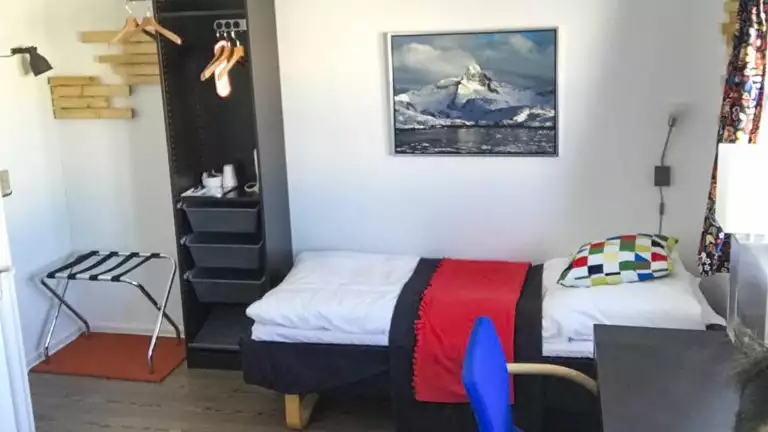 Room with bed, desk, chair, dresser at Hotel Angmagssalik in East Greenland