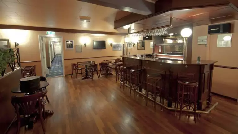 The bar with wooden seat-back stools and high-tops inside the Hotel Kulusuk, a remote and comfortable lodge in Greenland