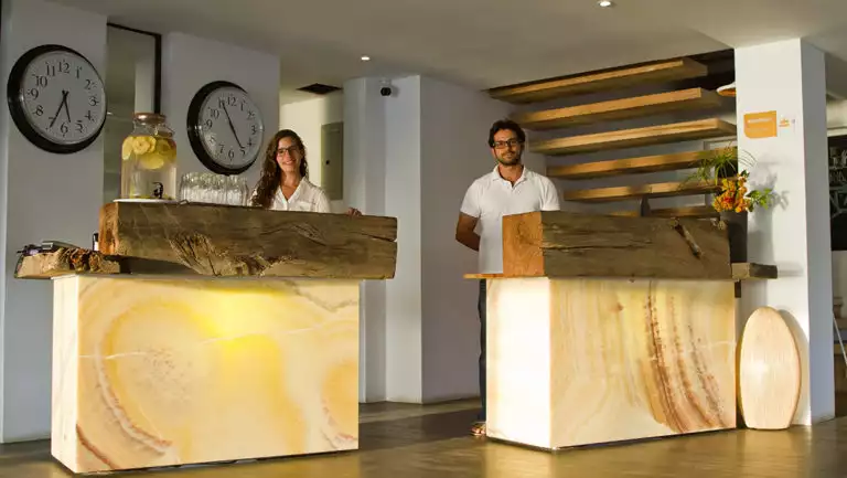 Woman and man waiting to help customers at reception area of Golden Bay Hotel & Spa on San Cristobal in the Galapagos Islands
