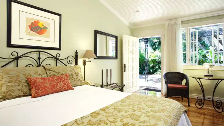 The superior room at Hotel Grano de Oro with a large, comfortable bed, fresh linens, and windows with a view of the jungle in Costa Rica