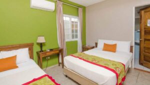 A double room with two queen-sized beds is bright and comfortable with green walls at La Casa de la Abuela, a relaxing hotel in Panama
