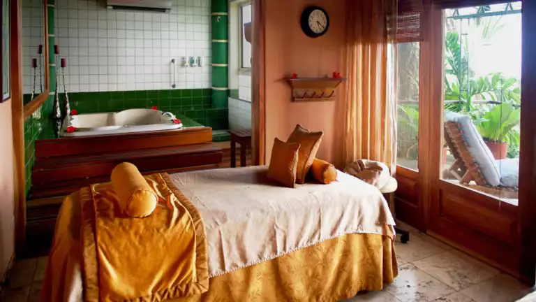 The massage table, draped in yellow sheets with pillows, is next to large windows looking toward the jungle at Si Como No Resort in Costa Rica
