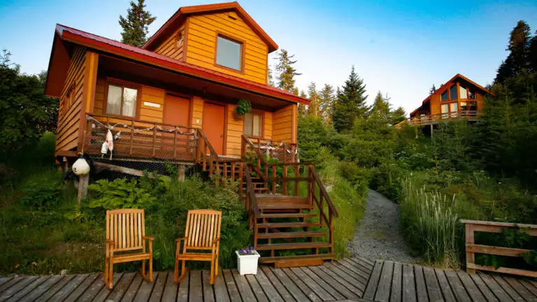 Stellar's Jay Cabin at Tutka Bay Lodge The Stellar's Jay Cabin with two rocking chairs on a patio in front, at the Tutka Bay Wilderness Lodge in Alaska