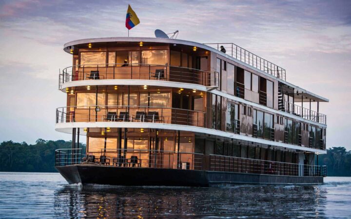 advantage travel anakonda luxury amazon ship sits in the river at dusk with the jungle in the background