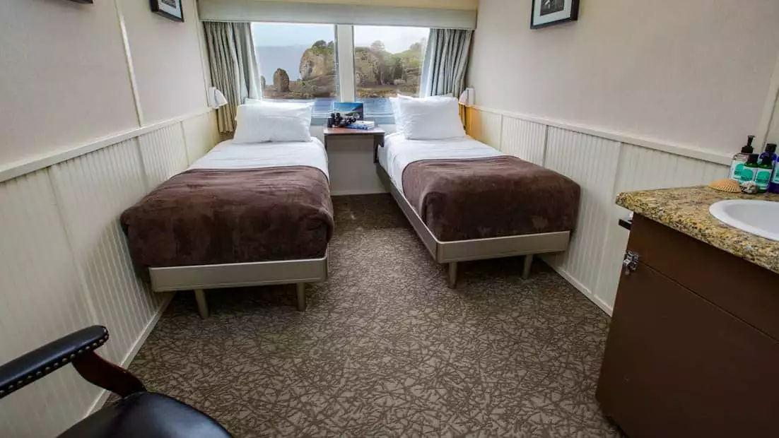 Category AAA stateroom aboard Alaskan Dream with two single beds and windo.