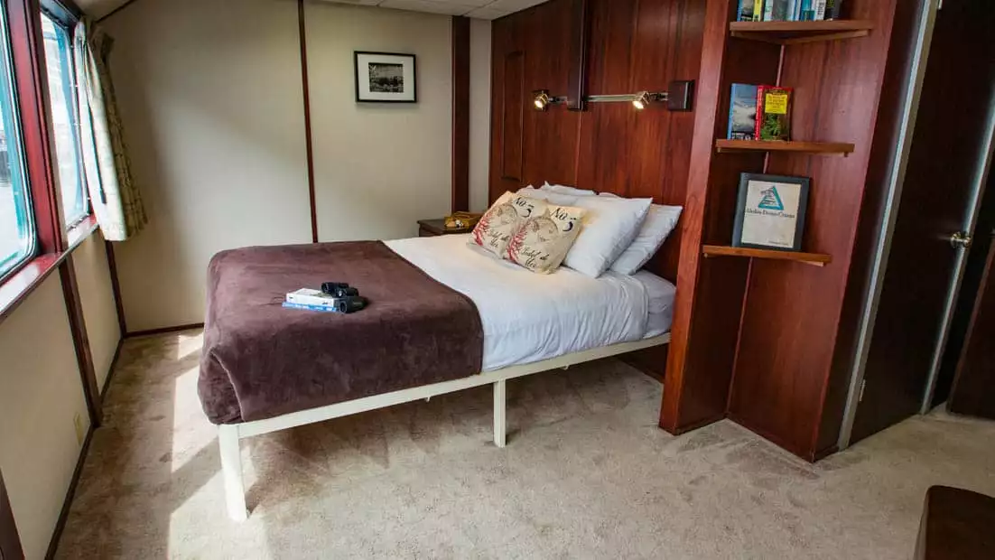 Owner's Suite aboard Alaskan Dream with large bed and window.