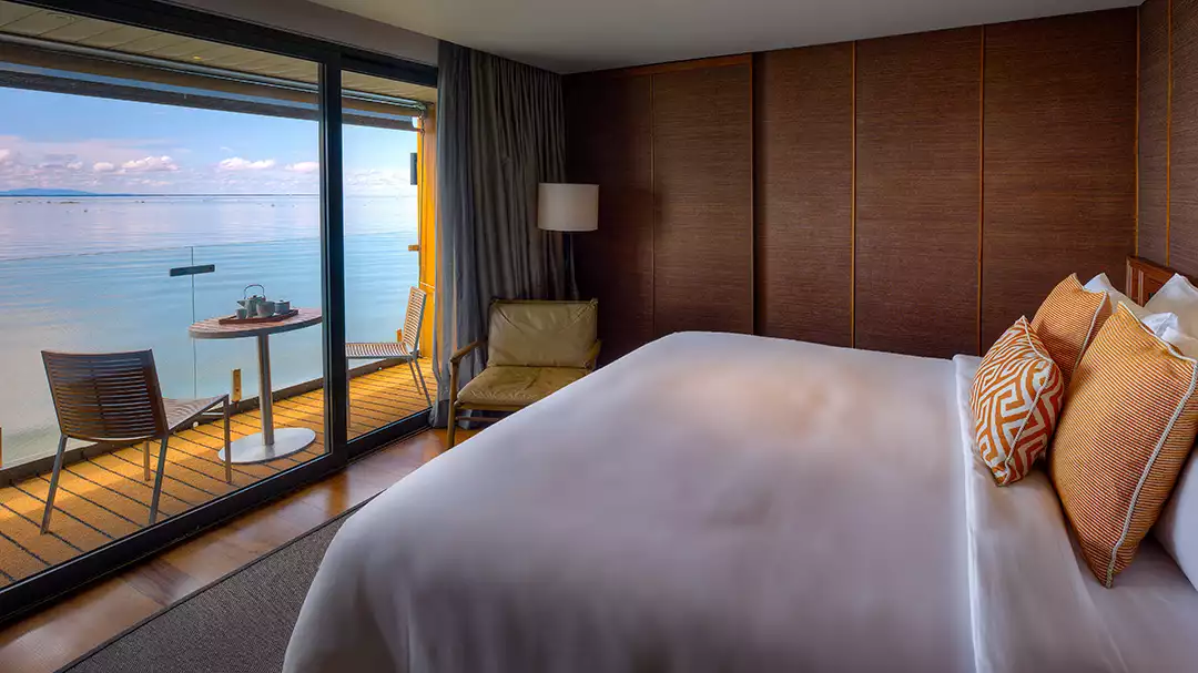 A beautiful suite on the first deck of the Aqua Mekong featuring a large bed with light linens and great views of the Mekong