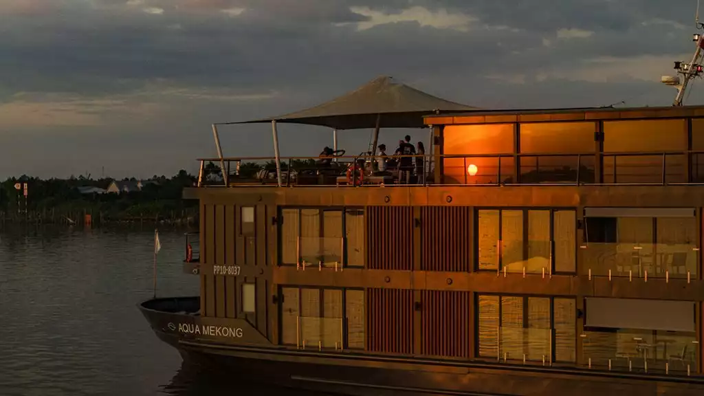 Aqua mekong ship crusing on calm waters with a sunset reflecction.
