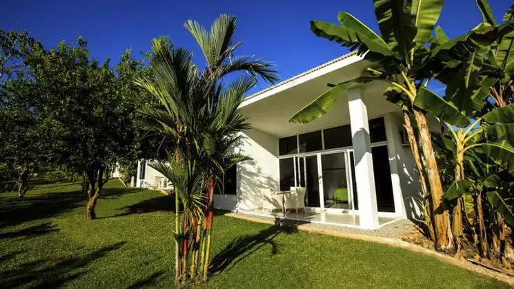 The exterior of the Bocas del Mar hotel with a green lawn, palm trees, and blue sky. A perfect day in Panama.