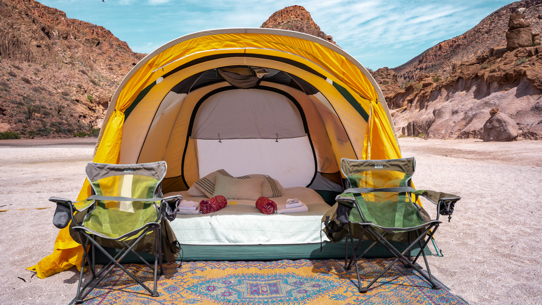 Yellow tent with queen-sized air bed, sheets & blankets, exterior woven mat & 2 camp chairs at Camp Cecil de la Isla, Baja.