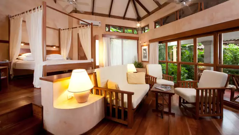A suite with a queen-sized bed, canopy, and sitting area, in the modern, beachfront Hotel Capitán Suizo at Playa Tamarindo, Costa Rica
