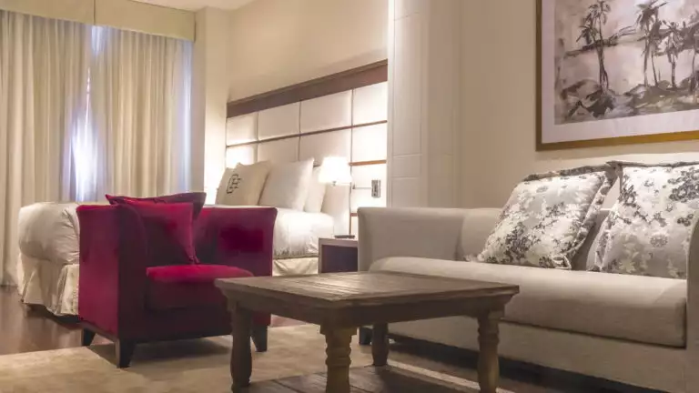 Couch, chair and coffee table near large bed in a Junior Suite at Central Hotel Panama in Panama City