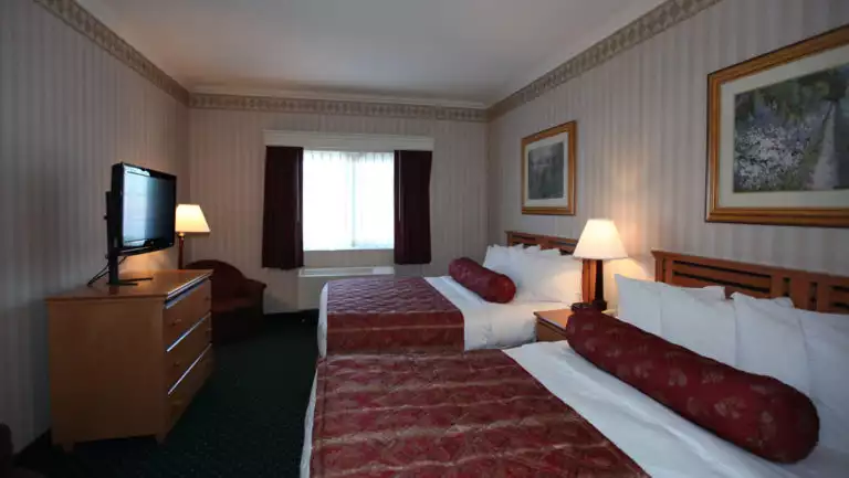Double room with two beds, dresser, nightstand, reading light and TV at Clarion Suites in Anchorage