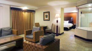 The Grand Spa Suite with a seating area, curtains, and a bed in an adjoining room at the four-star Hotel Presidente, in downtown San José, Costa Rica