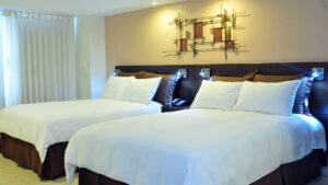 The Standard Room with two full beds, white comforters, and lighting at the four-star Hotel Presidente, in downtown San José, Costa Rica
