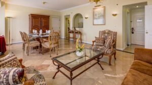 master suite in the las americas hotel in guatemala with marble floors, two tables, chairs and a couch with pictures on the walls